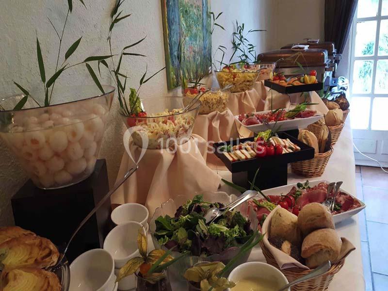 Buffet varié avec salades, fruits, pains et plats froids disposés sur une table décorée.