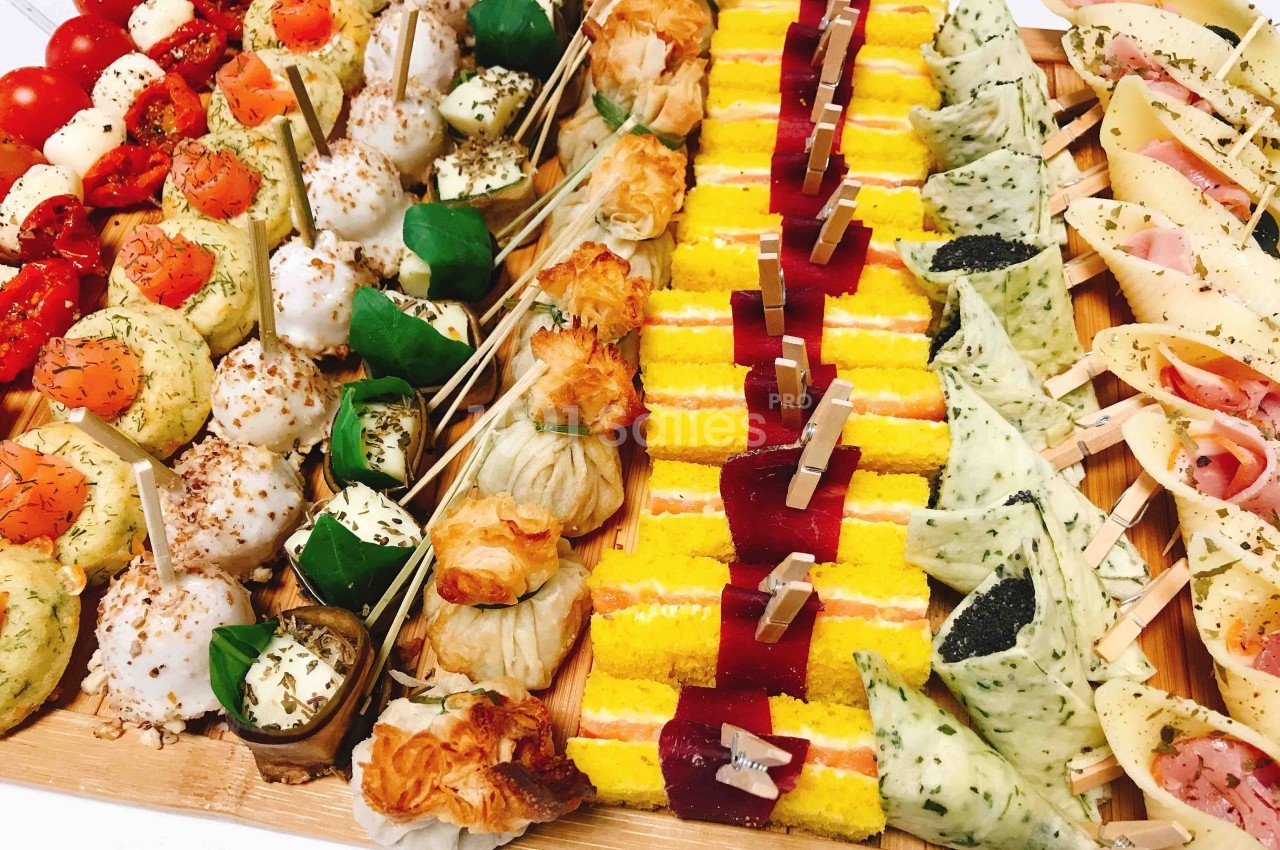 Plateau de bouchées apéritives variées comprenant légumes, fromages, feuilletés et amuse-bouches colorés.
