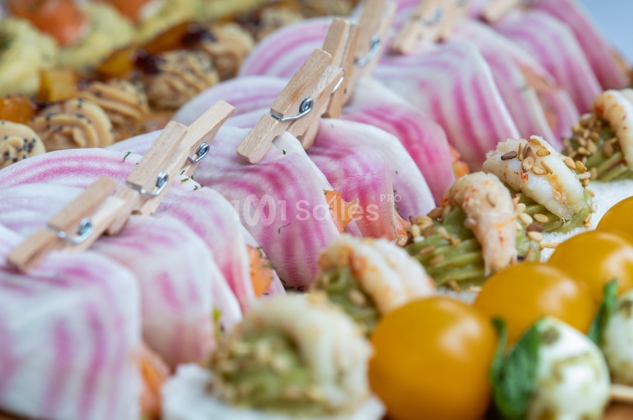 Assortiment de bouchées colorées avec légumes, crevettes, tomates cerises et décorations originales en pinces à linge.