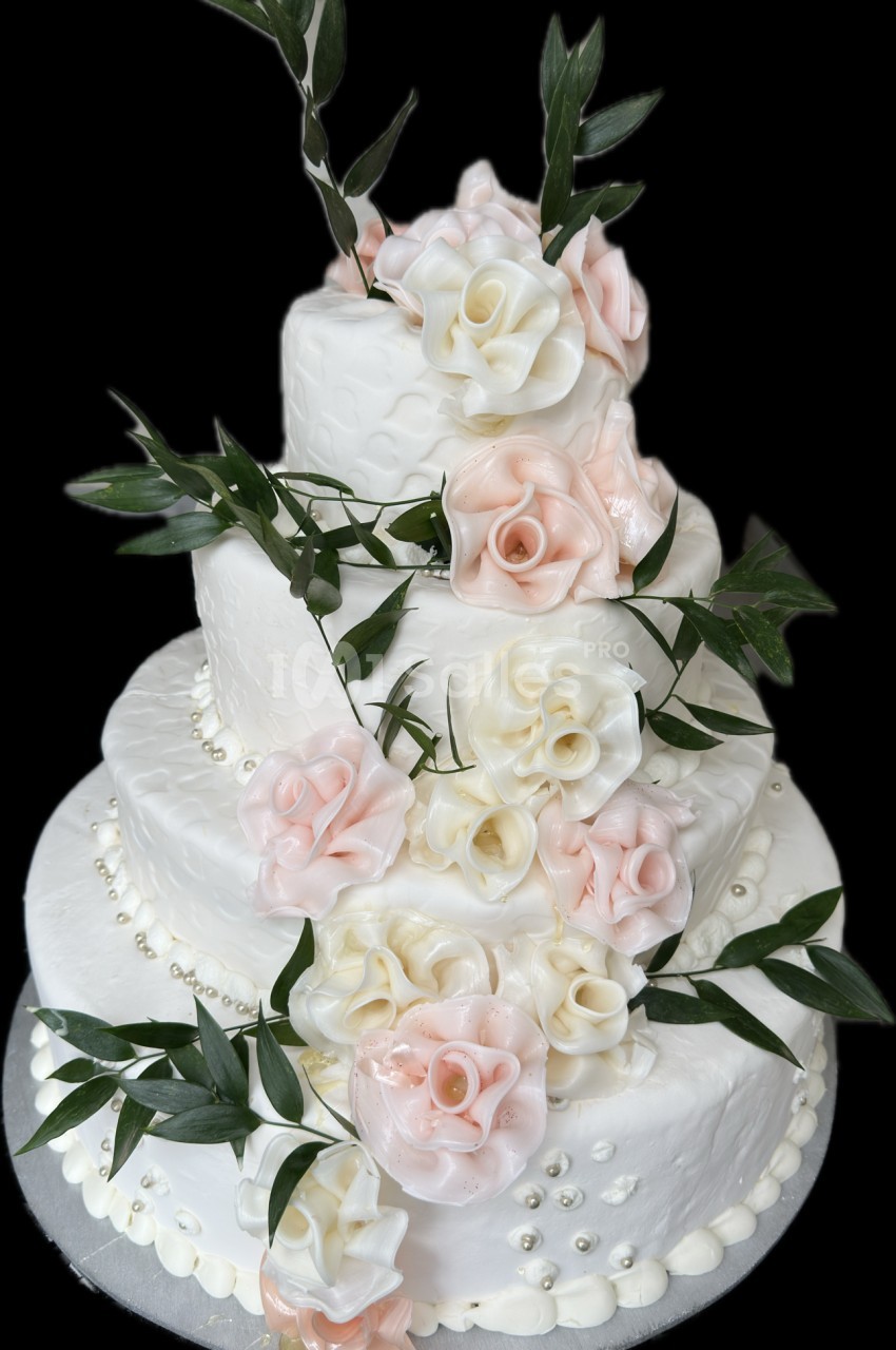 Gâteau de mariage à trois étages décoré de fleurs en sucre roses et blanches avec des feuilles vertes.