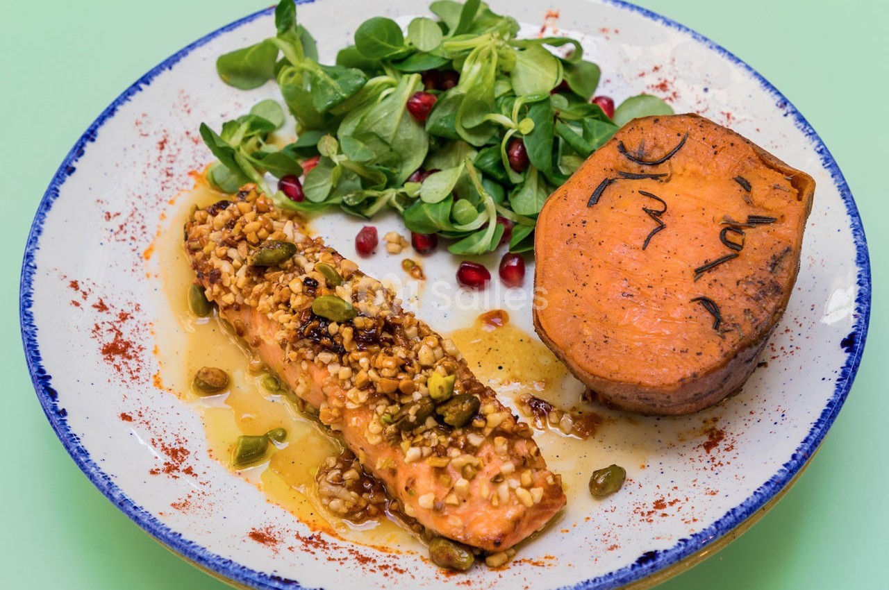 Assiette avec filet de saumon en croûte de pistaches, patate douce grillée et salade de mâche avec graines de grenade.