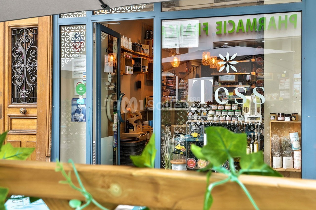 Façade d'une boutique avec vitrine affichant ’Tess’, entourée de plantes et d'éléments de décoration extérieure.