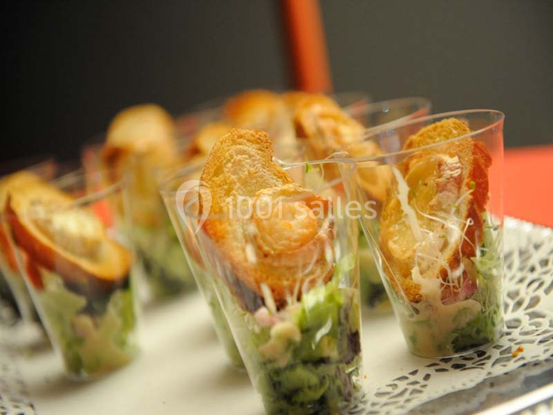 Verrines garnies de salade, crudités, fromage râpé et tranches de pain grillé, présentées sur un plateau.