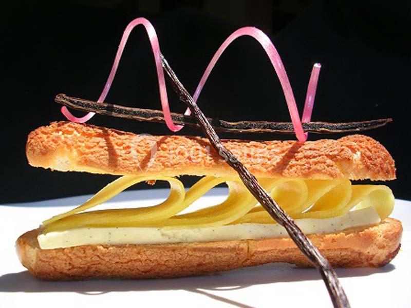 Éclair revisité garni de crème à la vanille, décoré de gousses de vanille et rubans de sucre rose.