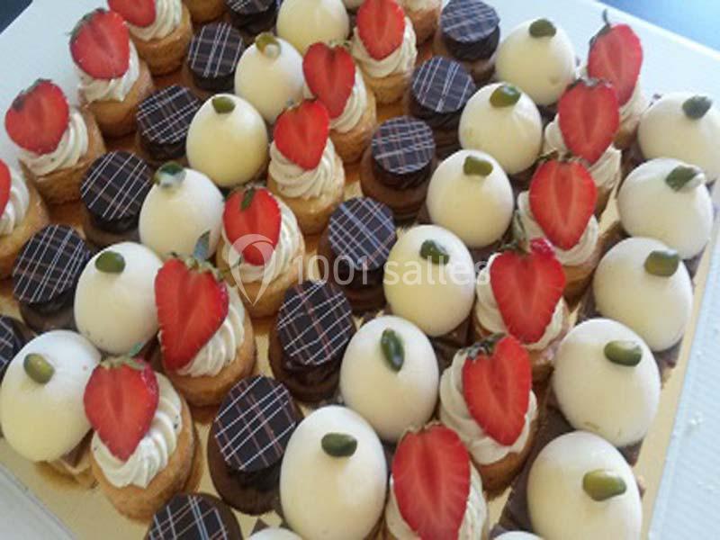 Plateau de mini-pâtisseries variées avec glaçages, fraises, pistaches et décorations en chocolat.