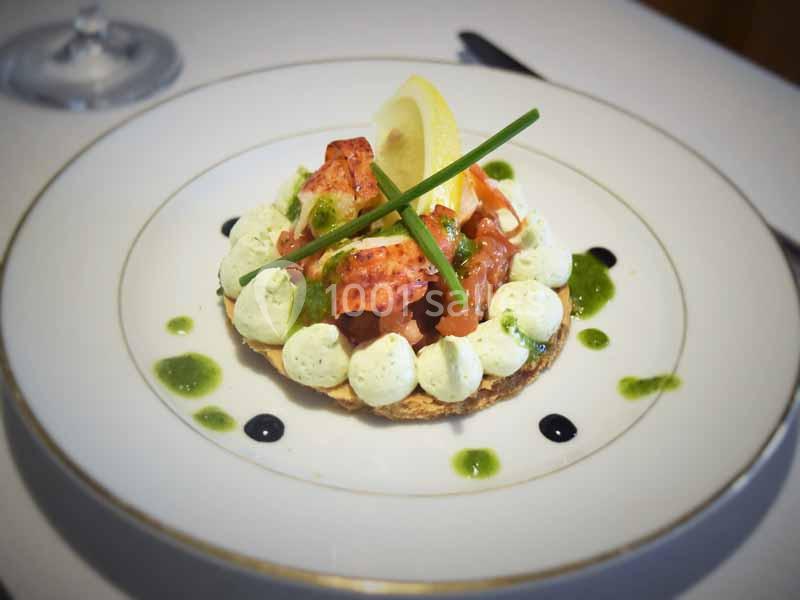 Tartelette garnie de saumon, mousse verte, citron et ciboulette, présentée sur une assiette blanche élégante.