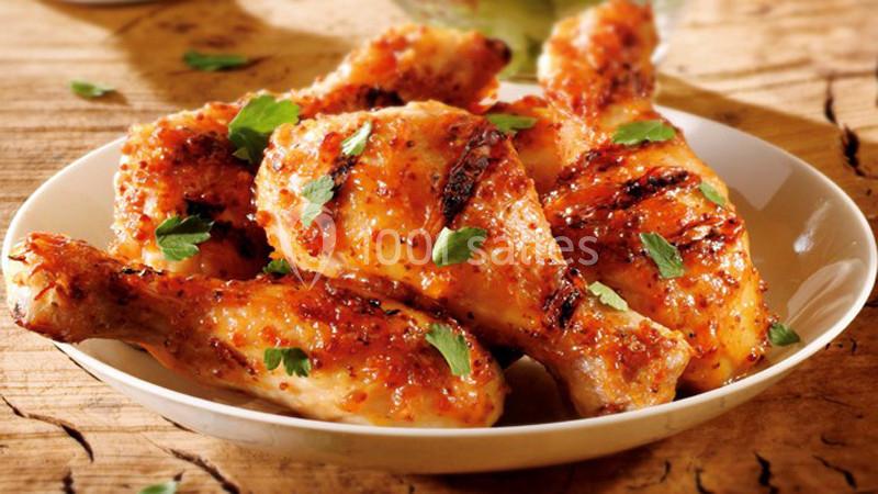 Morceaux de poulet grillés avec une marinade épicée, garnis de feuilles de persil, servis dans une assiette blanche.