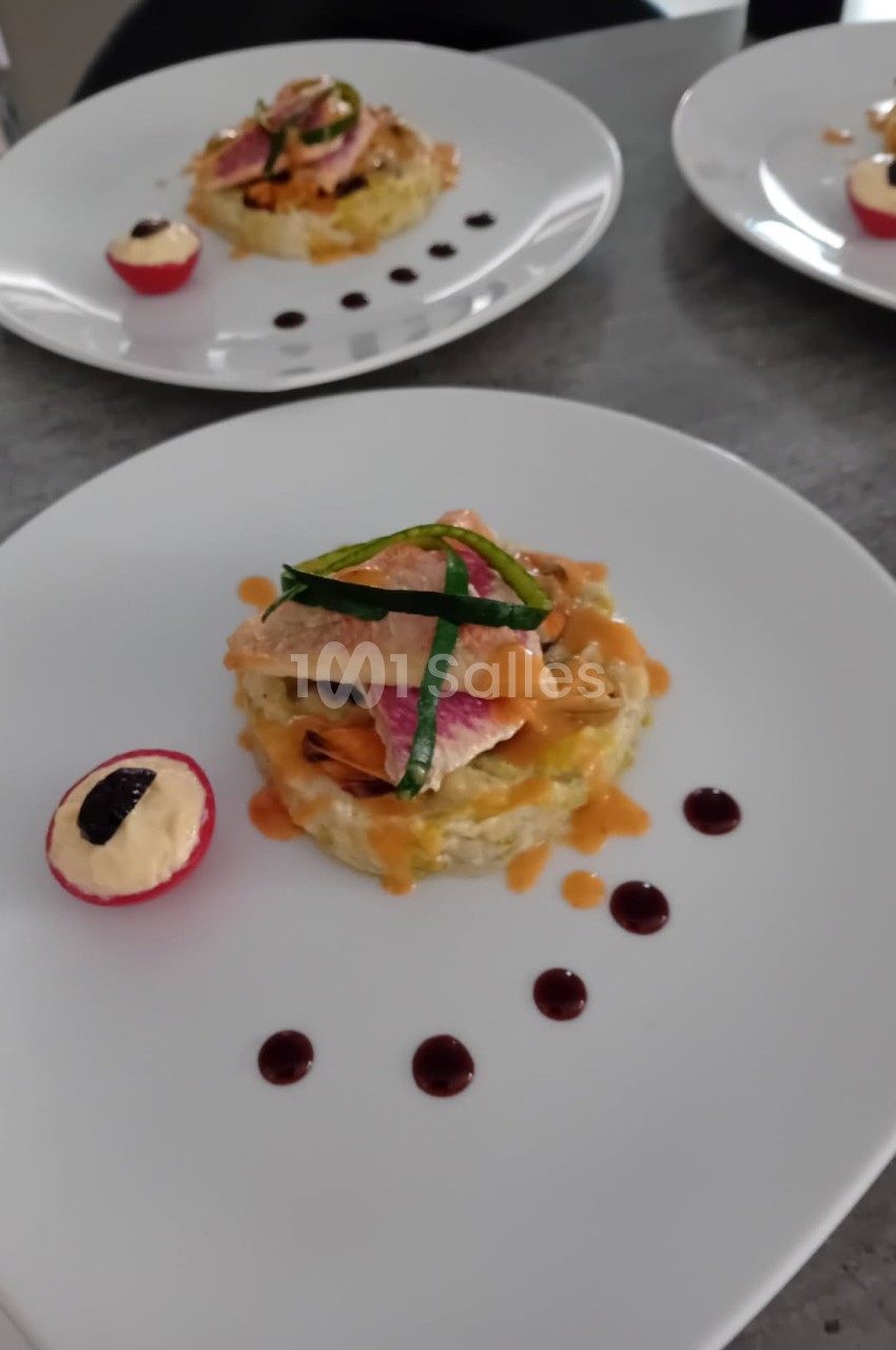 Assiette dressée avec un plat raffiné composé de poisson, légumes, sauce et une garniture de radis farci.