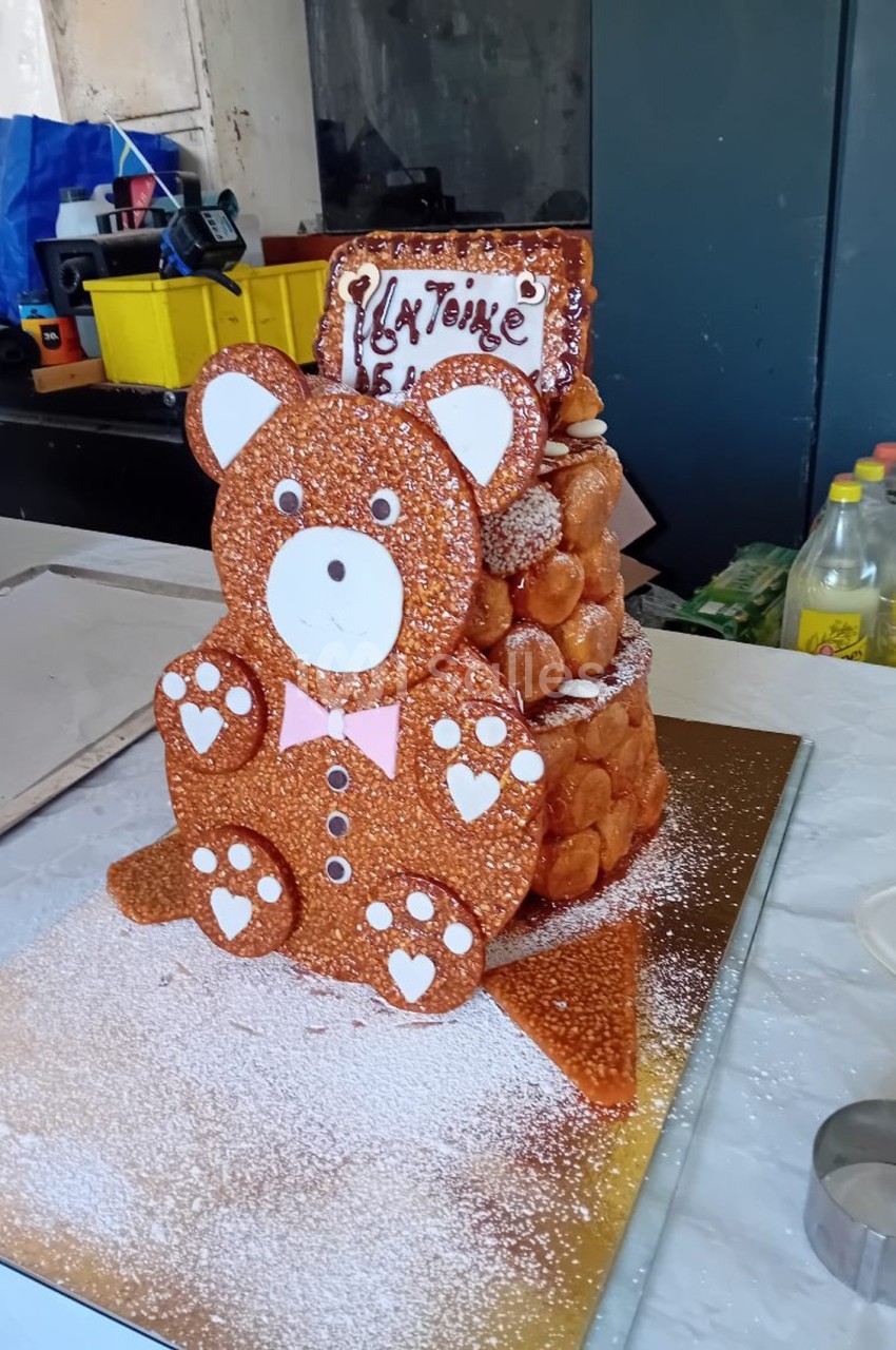 Pièce montée en forme d'ourson en nougatine et choux, décorée de sucre glace et d'un message en chocolat.