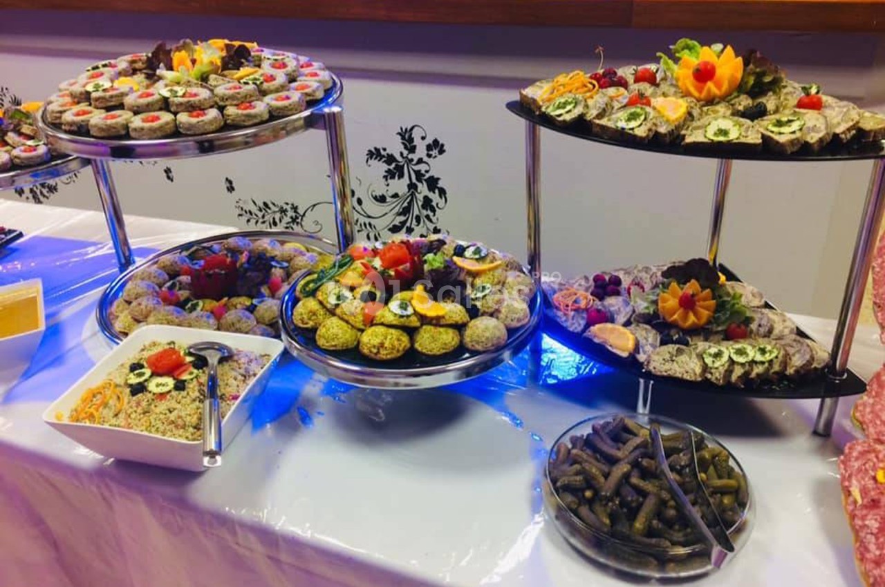 Buffet composé de plateaux de sushis, légumes farcis, salades et cornichons, présenté sur une table décorée.