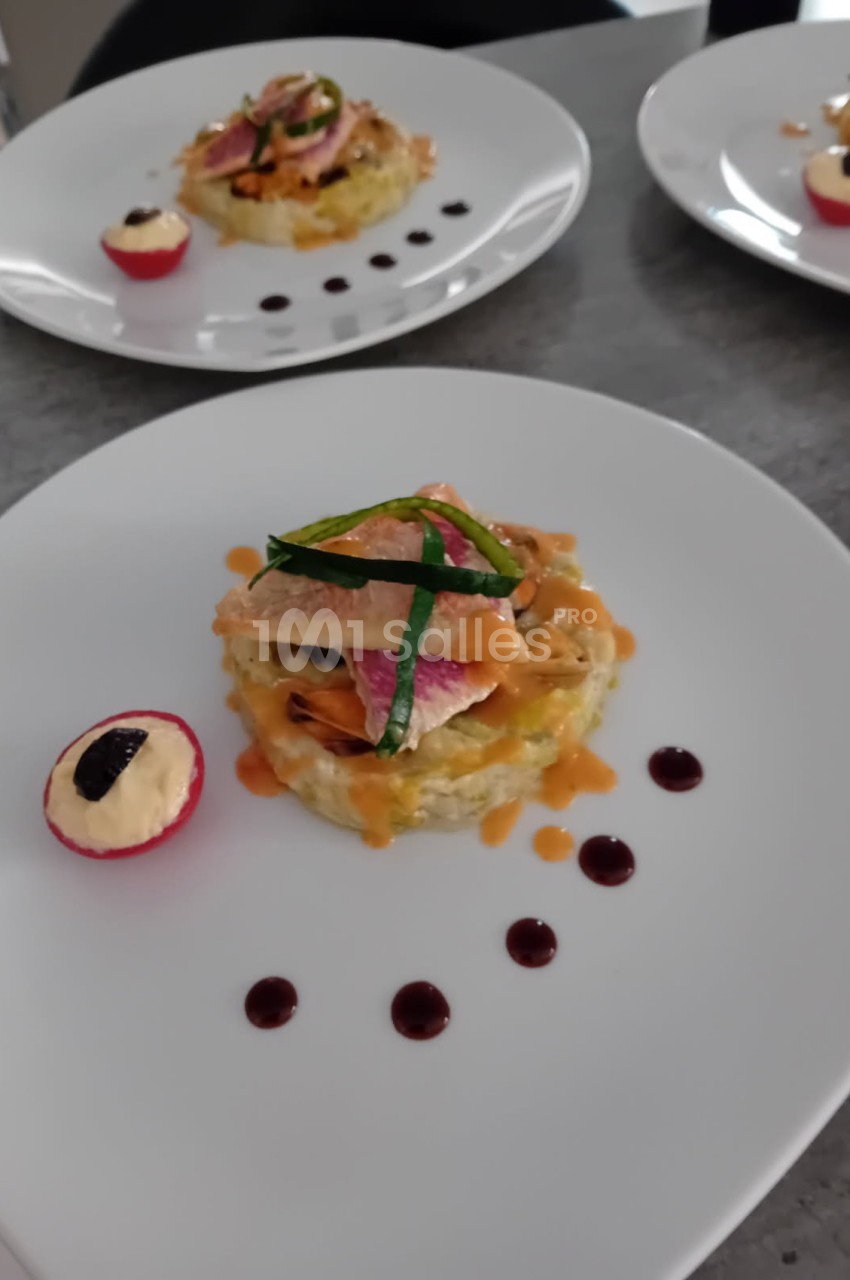 Assiette dressée avec un plat raffiné composé de poisson, légumes, sauce et une garniture de radis farci.