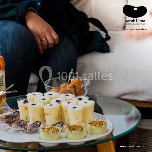 Plateau de desserts brésiliens variés sur une table basse, avec une personne assise en arrière-plan.