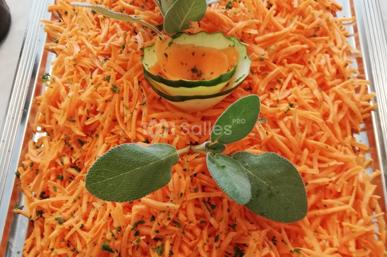 Salade de carottes râpées garnie de feuilles de sauge et d'une décoration en rondelles de concombre.
