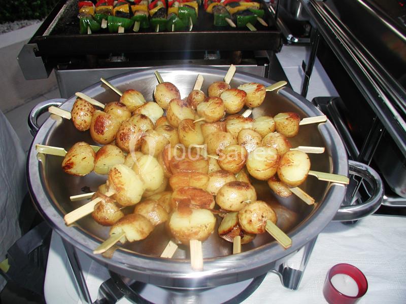 Brochettes de pommes de terre rôties présentées dans un plat en métal lors d'un buffet.