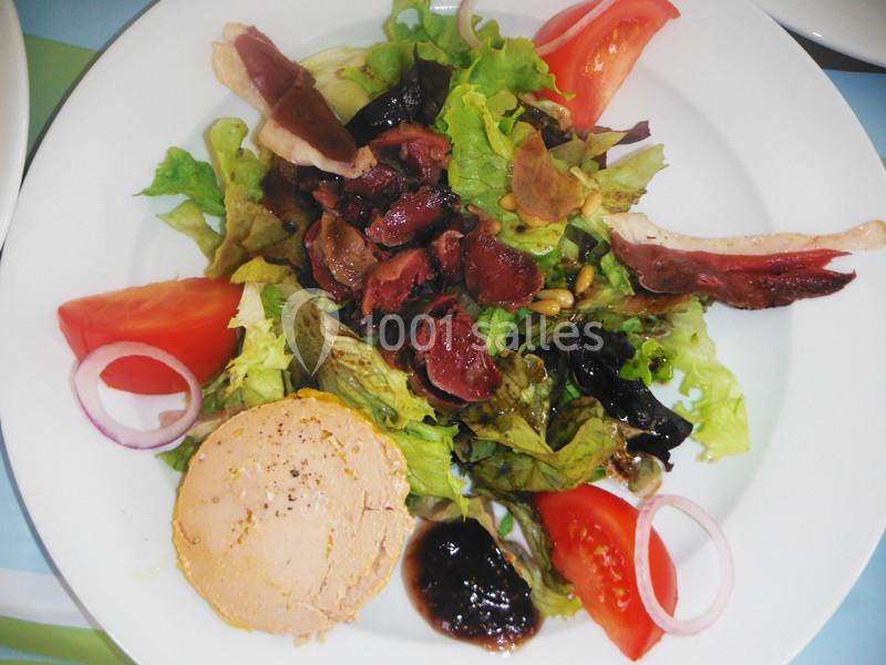 Assiette de salade composée avec foie gras, magret de canard, tomates, oignons rouges et vinaigrette.