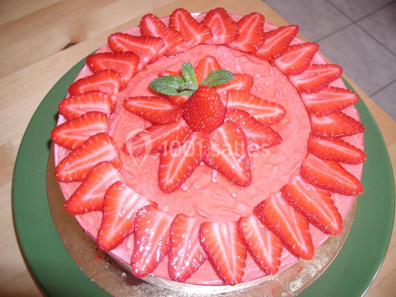 Gâteau décoré de tranches de fraises disposées en cercle avec une fraise entière et une feuille de menthe au centre.