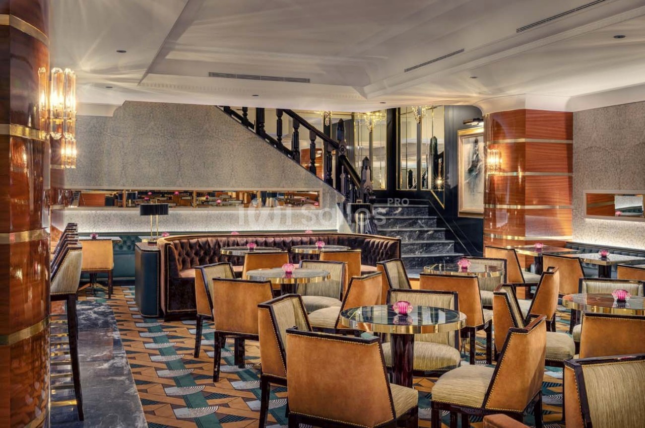 Salle de restaurant élégante avec des tables rondes, des chaises rembourrées et un éclairage chaleureux.