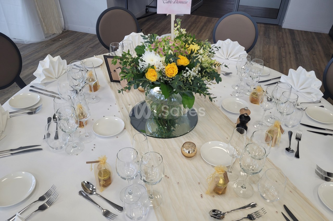 Table dressée pour un repas festif avec nappes blanches, vaisselle élégante et centre de table floral coloré.