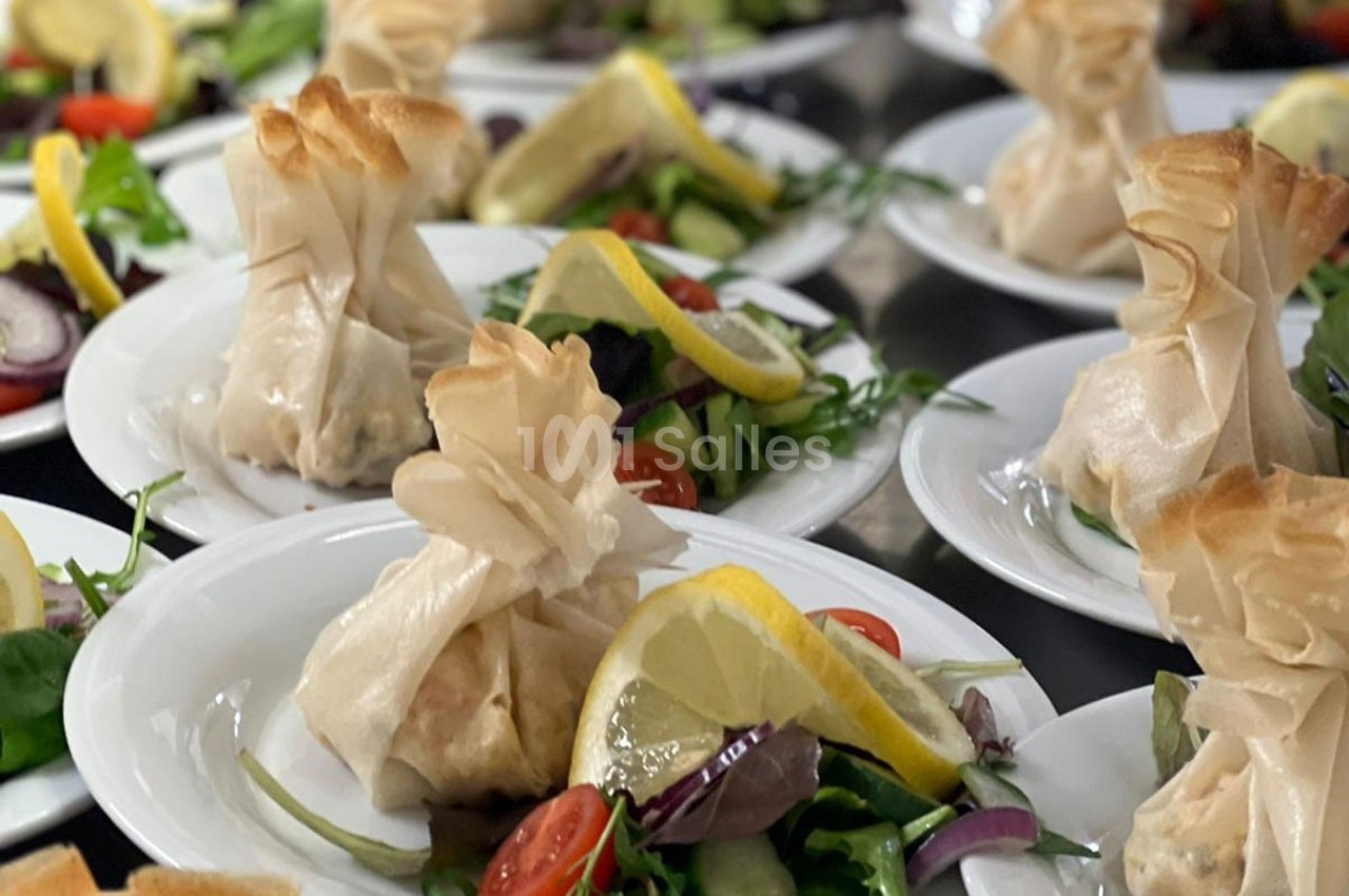 Assiettes garnies de feuilletés en aumônière accompagnés de salade verte, tomates cerises et tranches de citron.