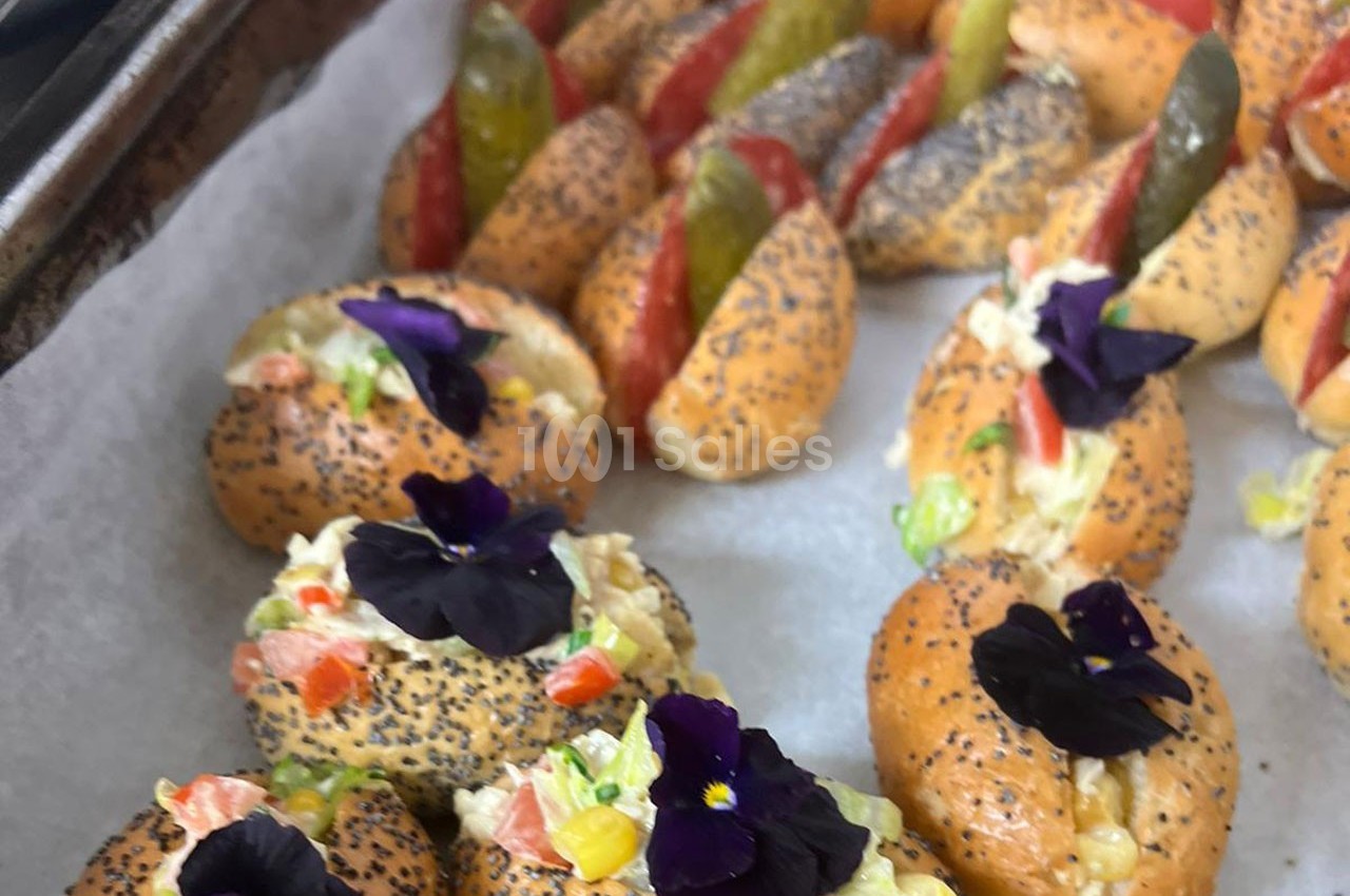 Petits pains garnis de salade colorée, décorés de fleurs comestibles et de graines de pavot.