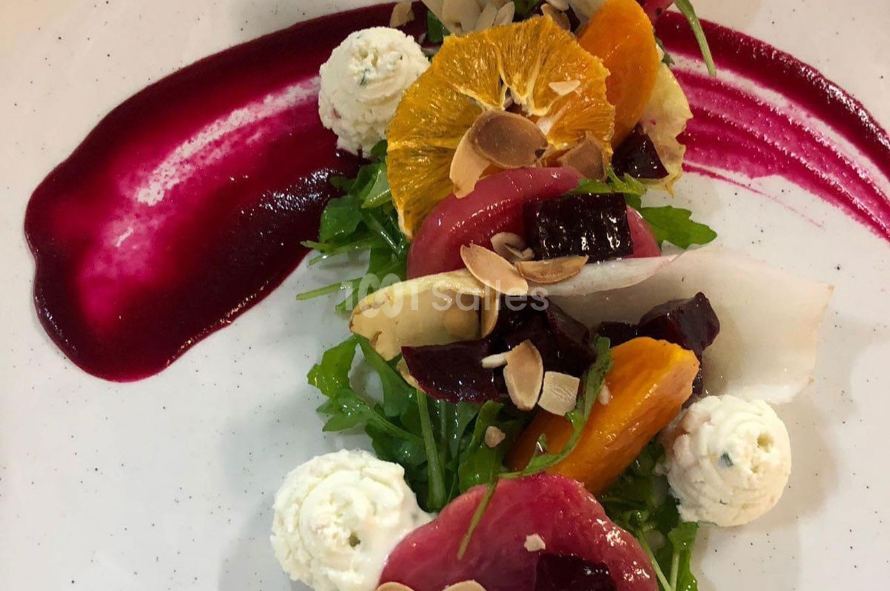 Salade colorée avec betteraves, oranges, fromage frais, amandes effilées et sauce rouge dressée en courbe.
