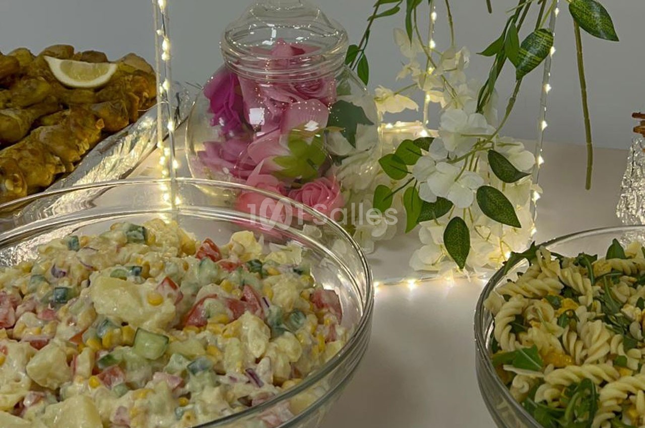 Assortiment de plats froids comprenant une salade de pommes de terre, une salade de pâtes et des dolmas, décorés de fleurs…