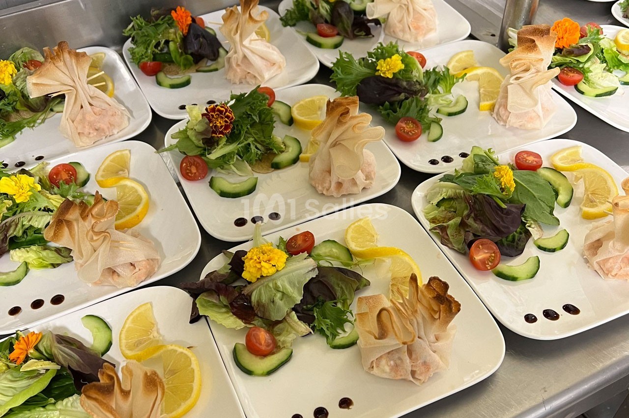 Assiettes dressées avec des aumônières dorées, salade verte, rondelles de concombre, tomates cerises et tranches de citron.