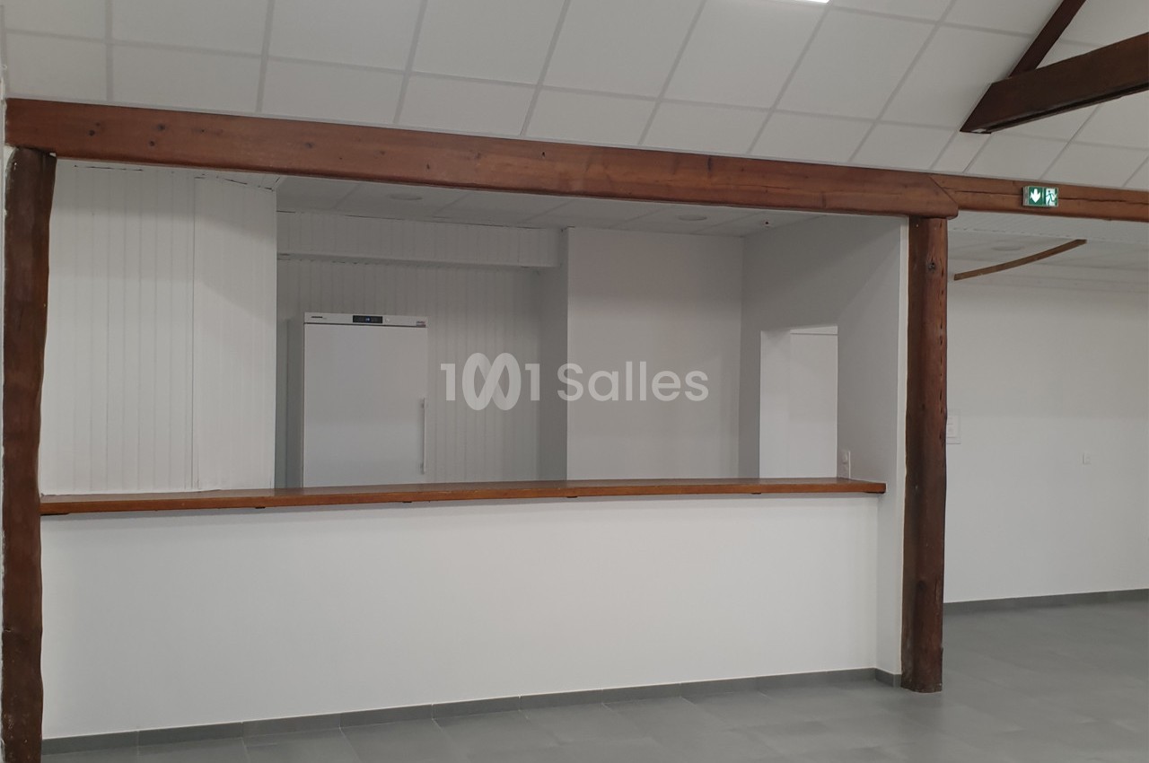 Espace intérieur avec comptoir en bois, murs blancs, plafond à dalles et sol en carrelage gris.