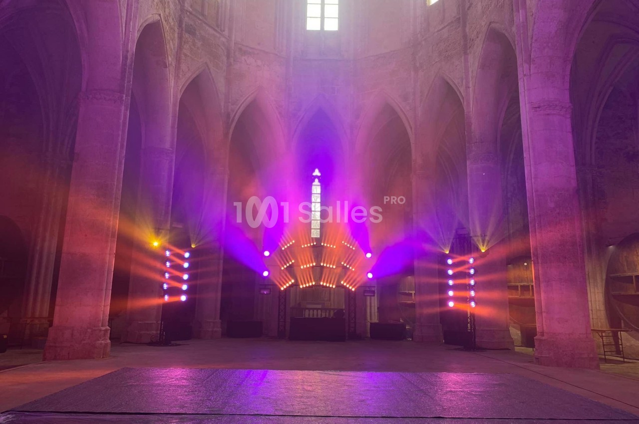 Éclairage coloré et lumineux dans une église gothique, mettant en valeur les arches et les vitraux.