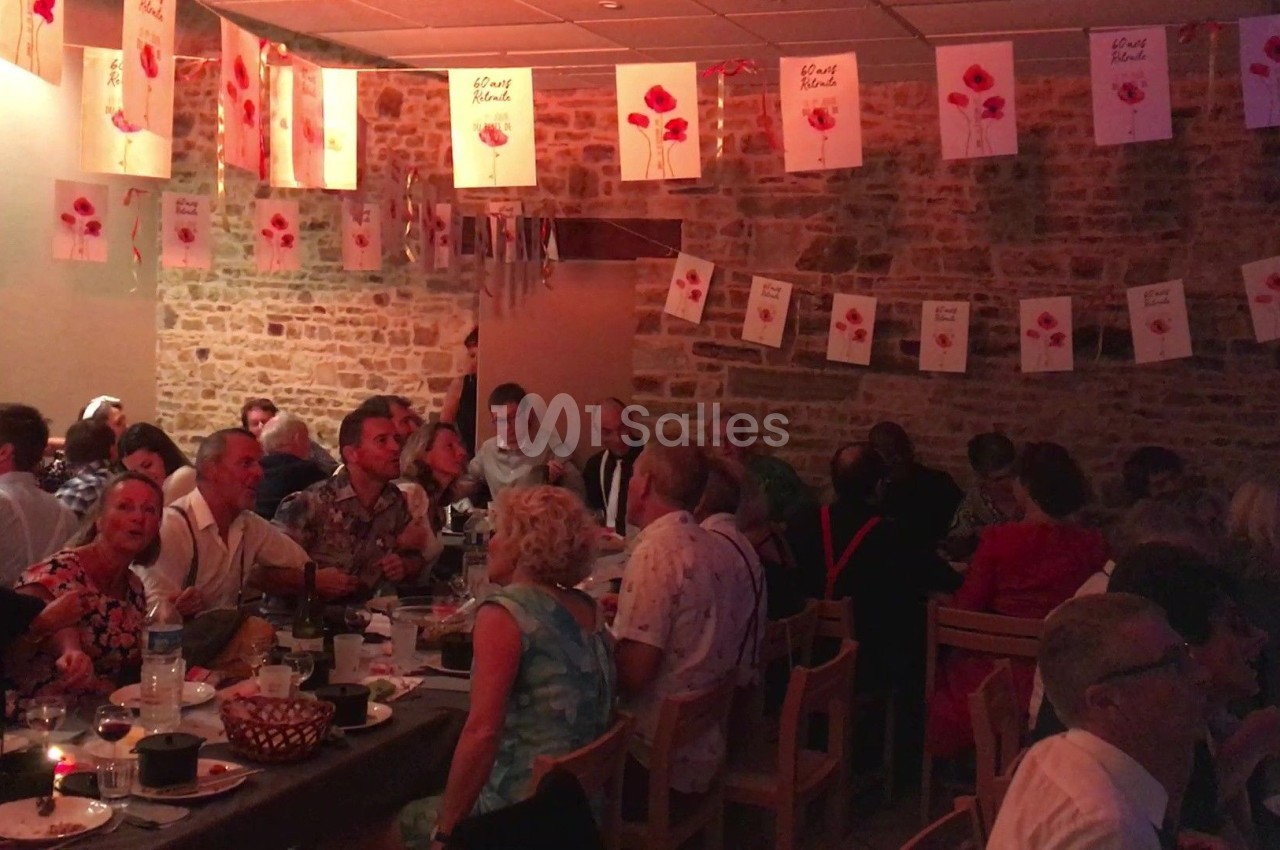 Des personnes assises à des tables dans une salle décorée de guirlandes et affiches avec des coquelicots.