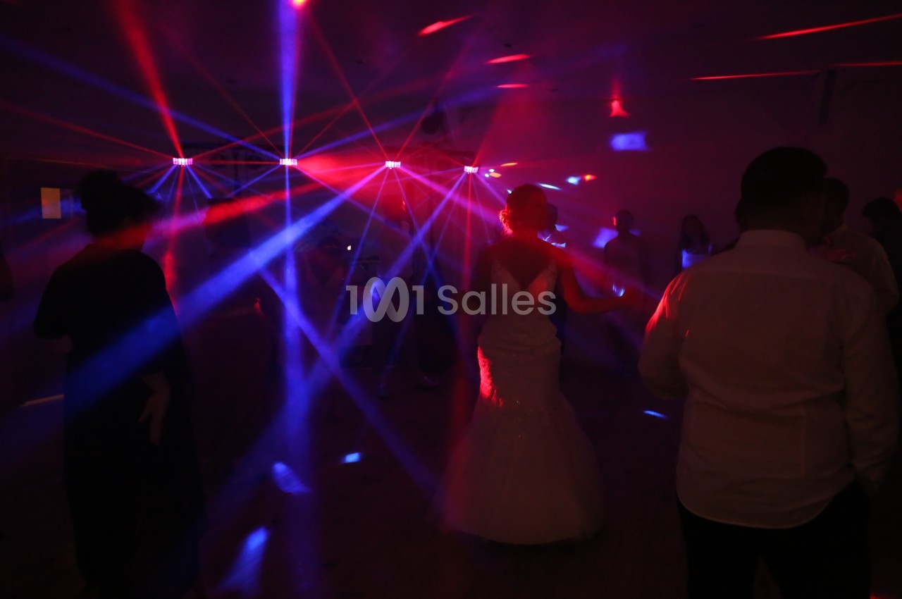 Des personnes dansent sous des lumières colorées et des faisceaux laser dans une ambiance festive.