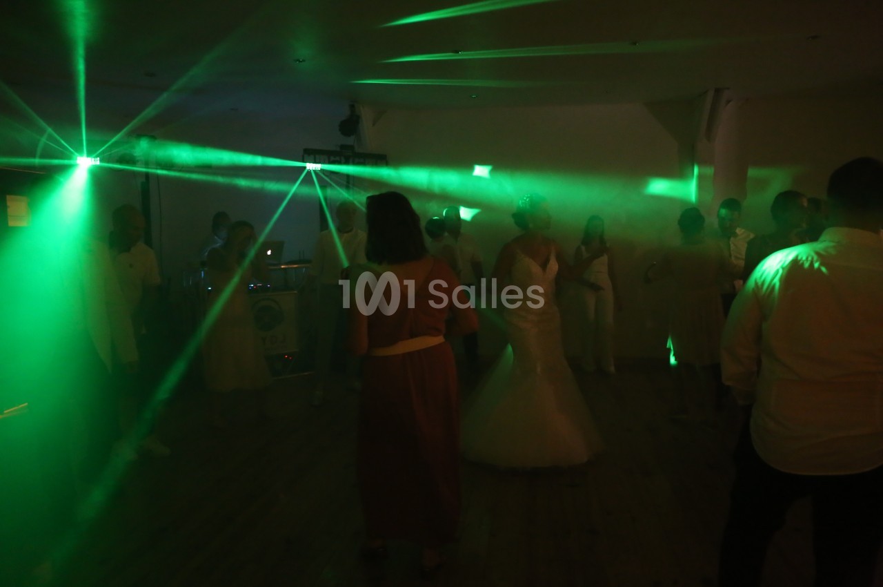 Des invités dansent sous des lumières vertes lors d'une soirée dans une salle sombre.