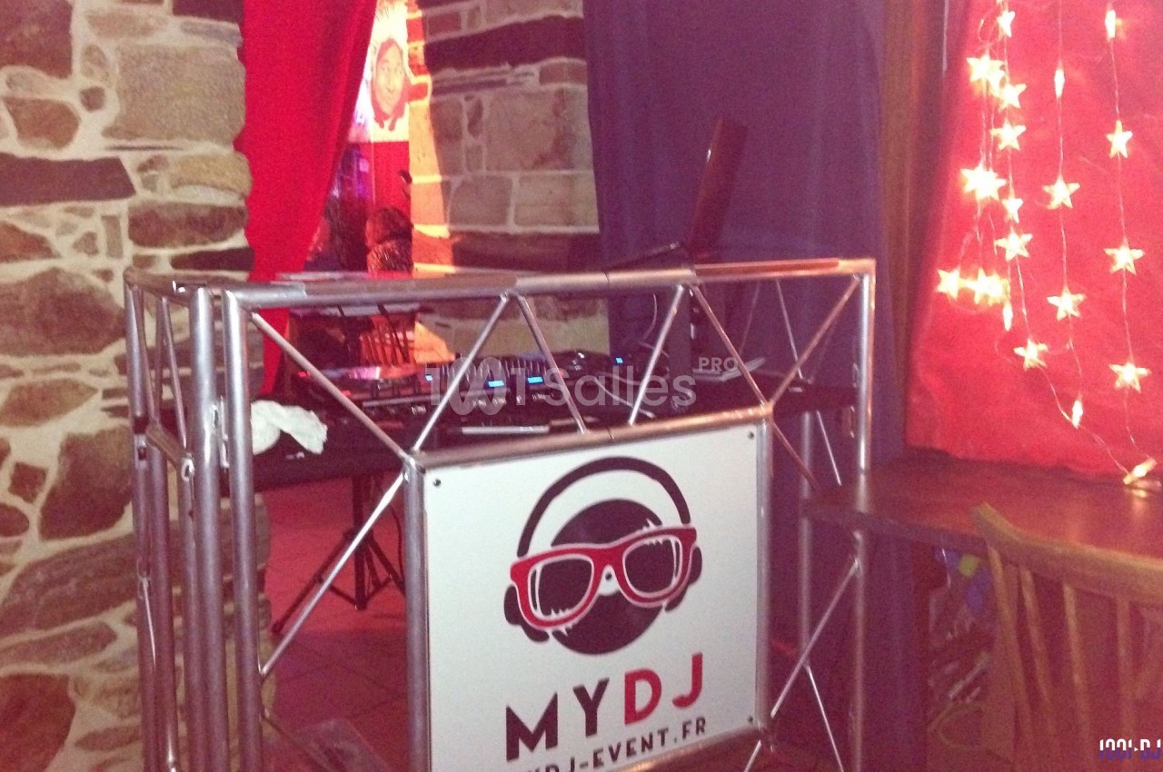 Console de DJ installée dans un cadre intérieur avec des murs en pierre et des rideaux rouges décorés d'étoiles.