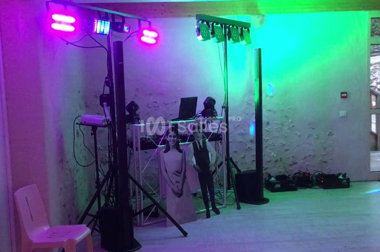 Installation de matériel de sonorisation et éclairage coloré dans une salle avec murs en pierre apparente.