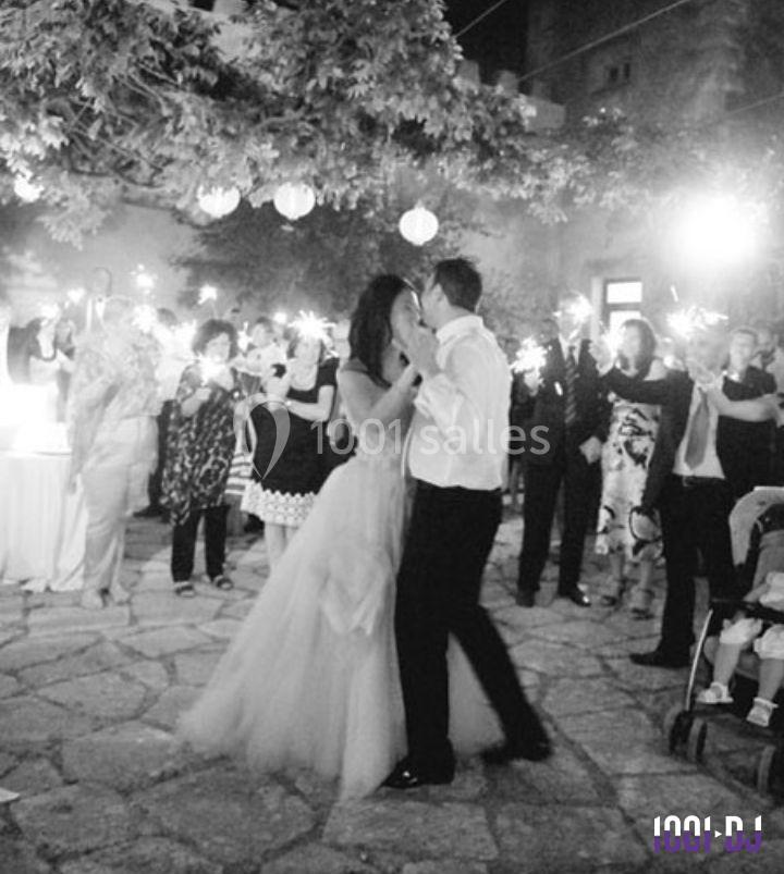 Un couple danse lors d'une réception en plein air, entouré d'invités tenant des cierges magiques.