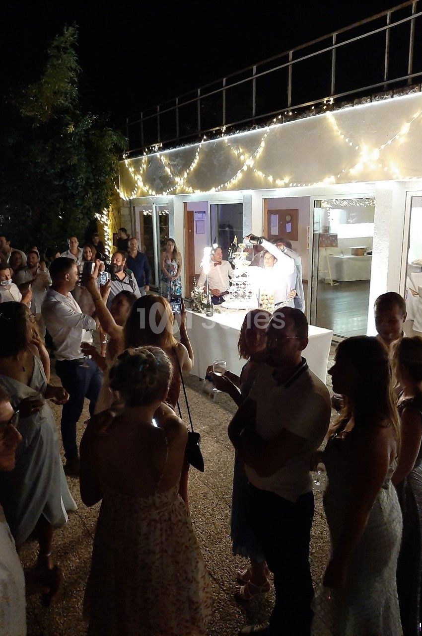 Groupe de personnes rassemblées en soirée devant une table éclairée, décorée de guirlandes lumineuses.