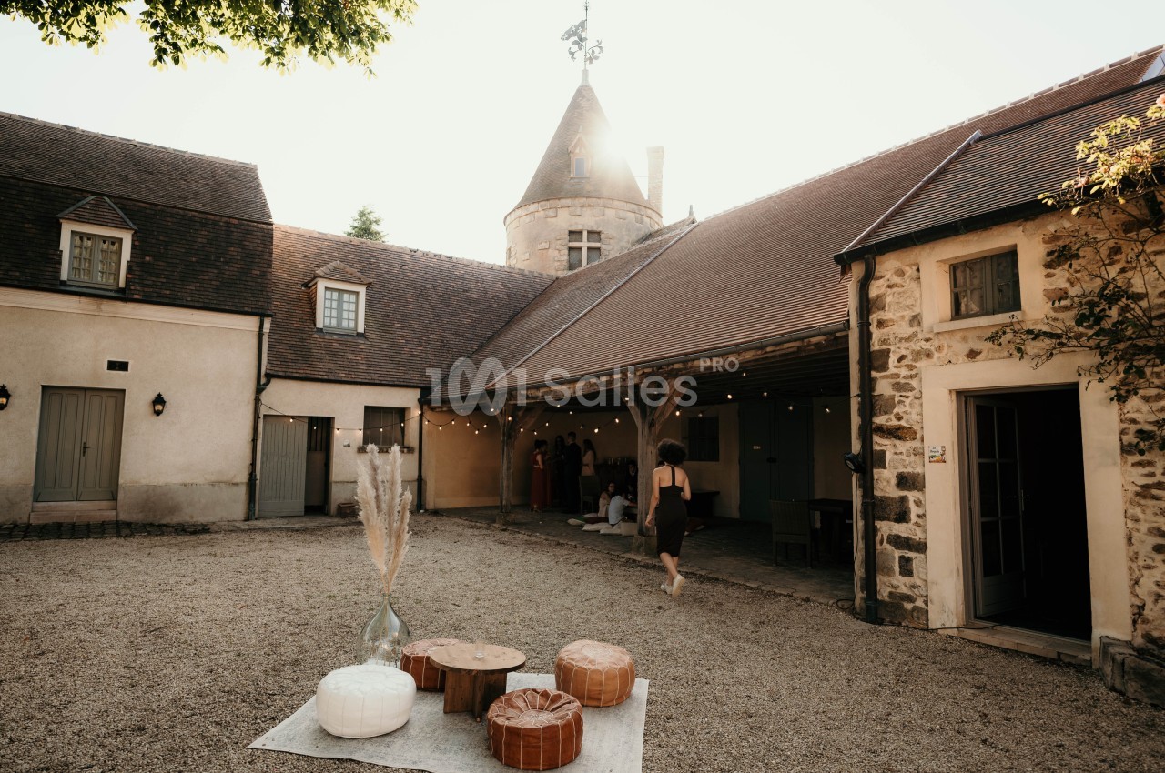Cour intérieure d'un bâtiment ancien avec une tour, des décorations et des invités sous un auvent éclairé.