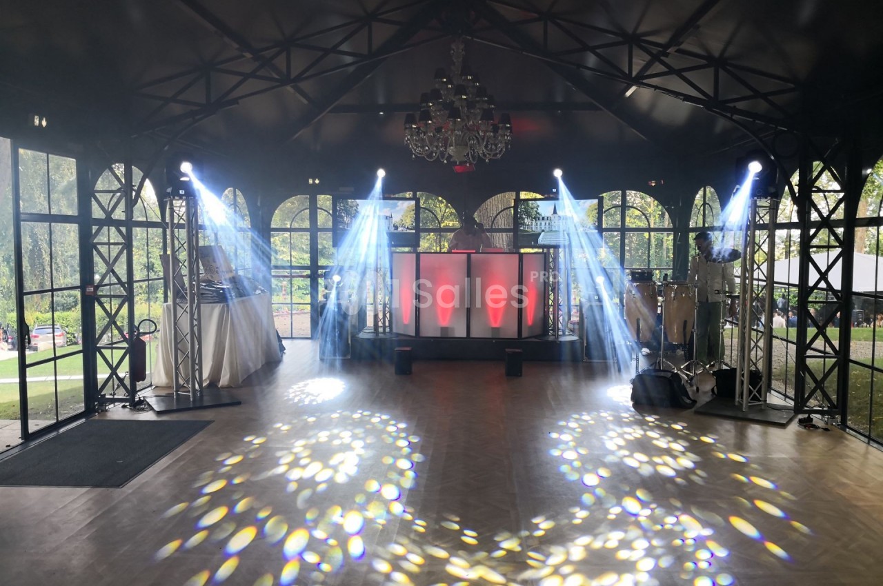 Salle de réception avec piste de danse, éclairages colorés et projecteurs créant des motifs lumineux au sol.