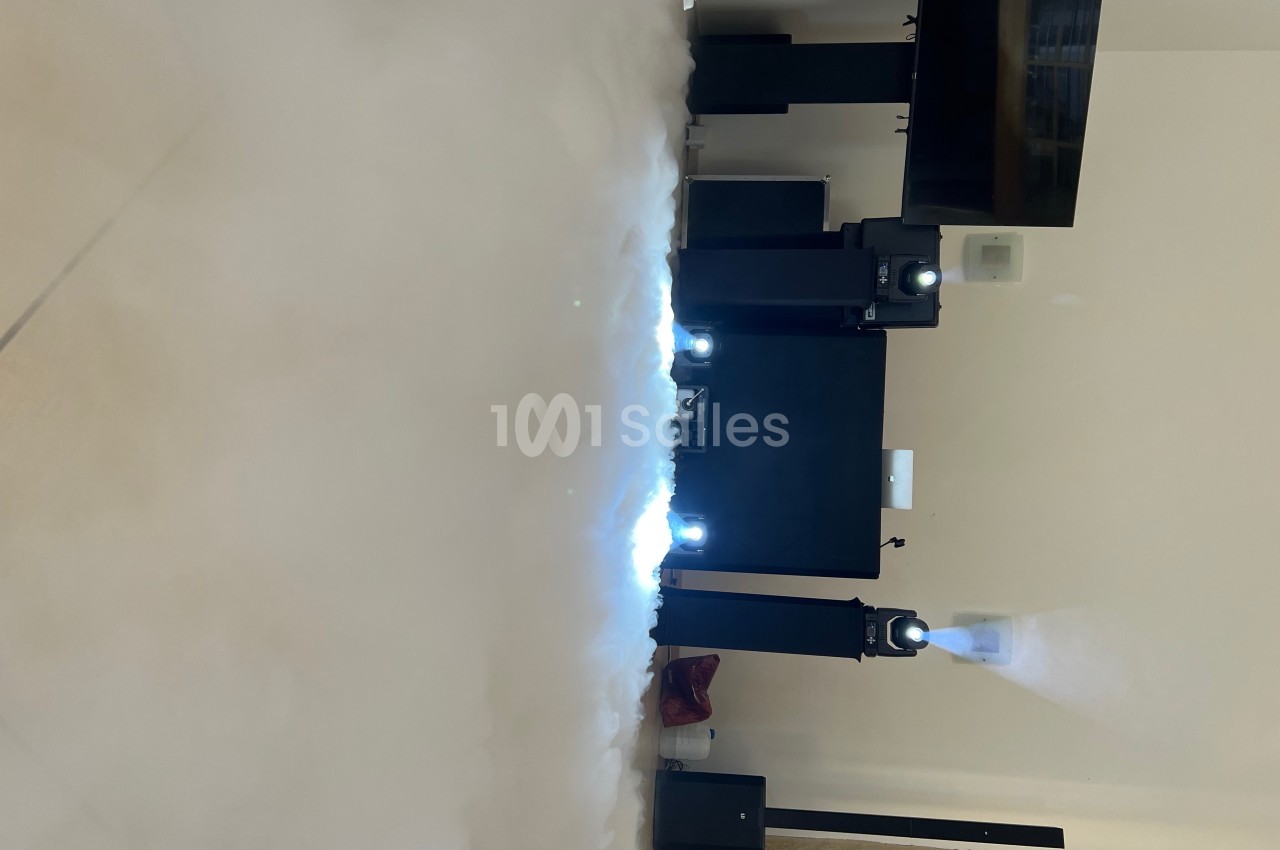 Installation de projecteurs lumineux dans une pièce, émettant des faisceaux à travers une légère fumée au sol.
