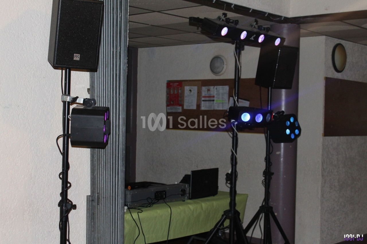 Équipement de sonorisation et éclairage installé dans une salle, avec table de mixage et projecteurs lumineux.