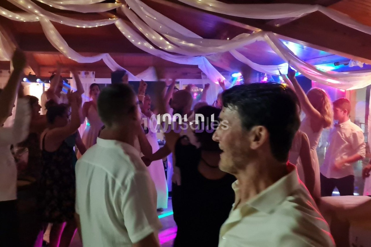 Groupe de personnes dansant dans une salle décorée avec des guirlandes lumineuses et un éclairage coloré.