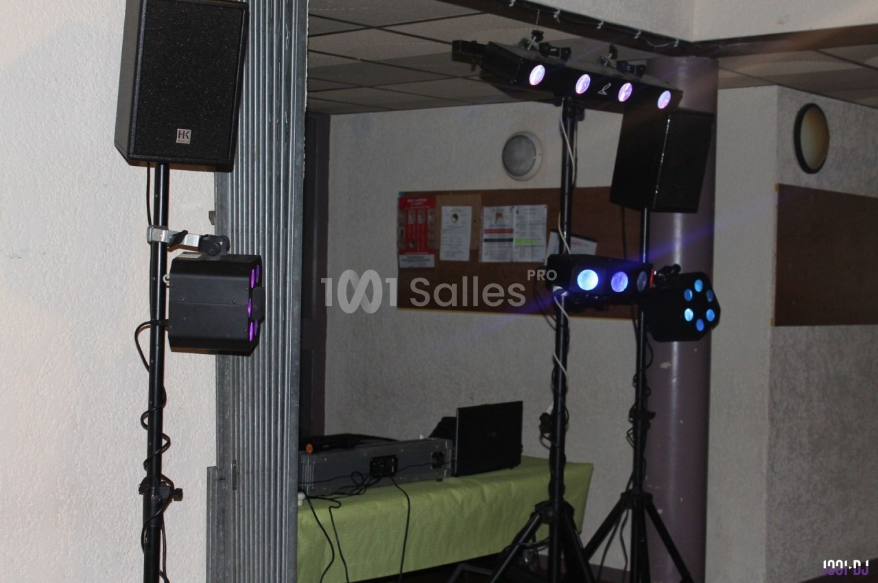 Équipement de sonorisation et éclairage installé dans une salle, avec table de mixage et projecteurs lumineux.