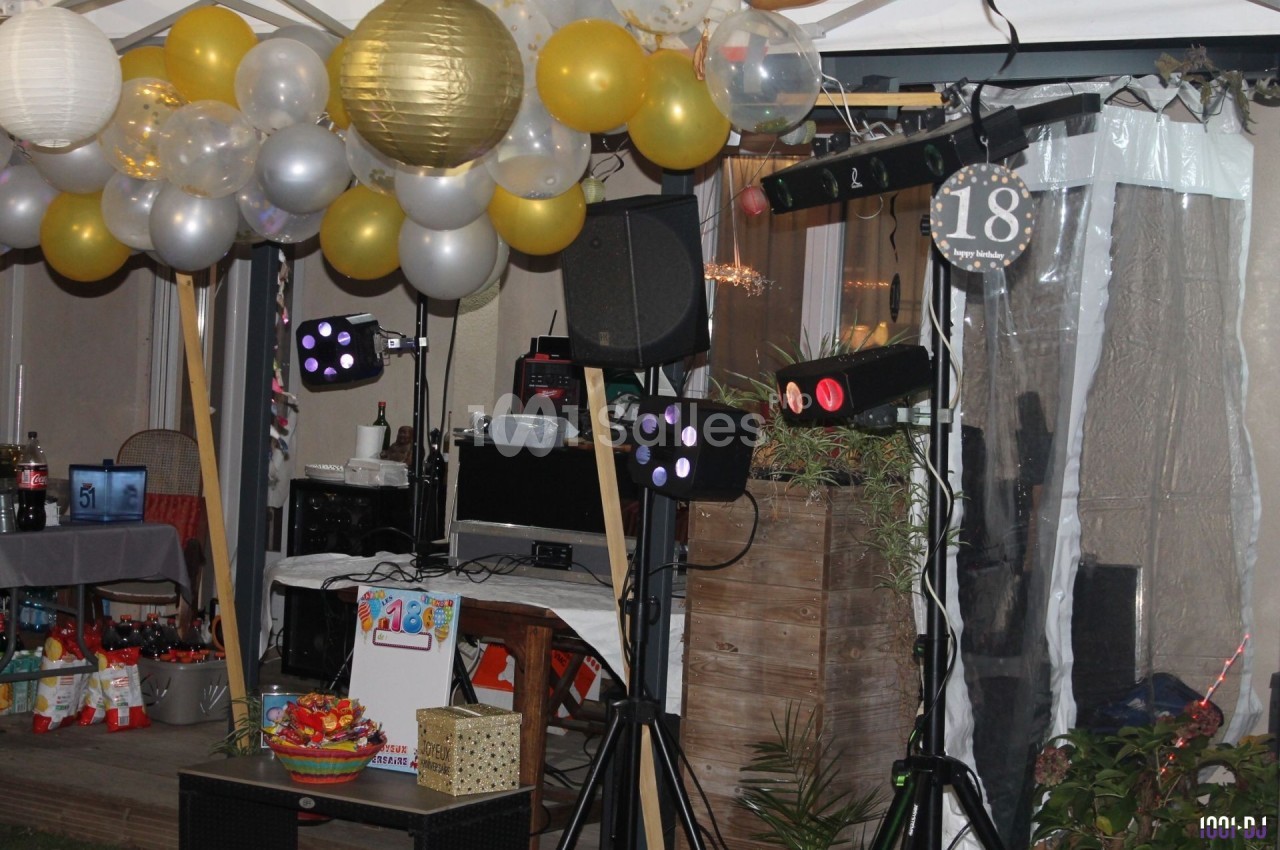 Décoration festive avec ballons, guirlandes lumineuses et équipement de sonorisation pour une fête en extérieur.
