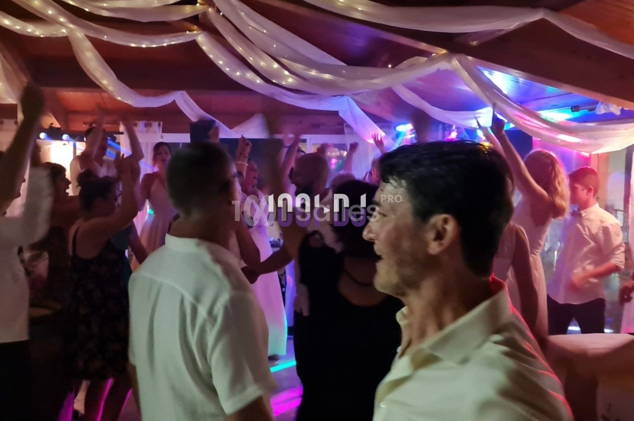 Groupe de personnes dansant dans une salle décorée avec des guirlandes lumineuses et un éclairage coloré.