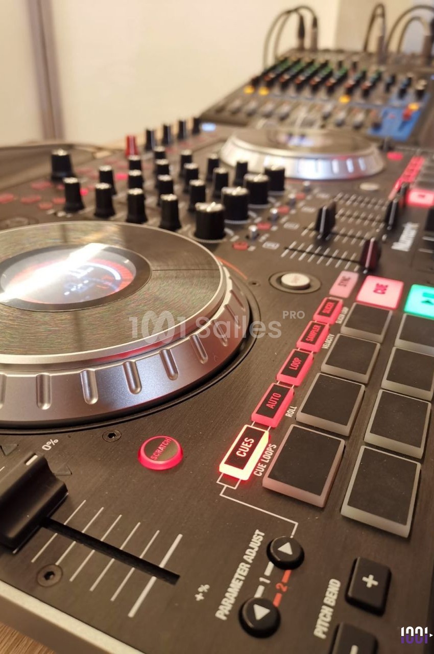 Table de mixage DJ avec platines, boutons et curseurs, connectée à une console audio en arrière-plan.
