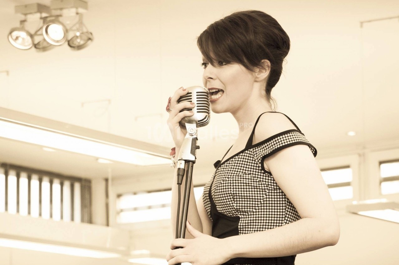 Une femme chante dans un microphone vintage dans un intérieur lumineux.