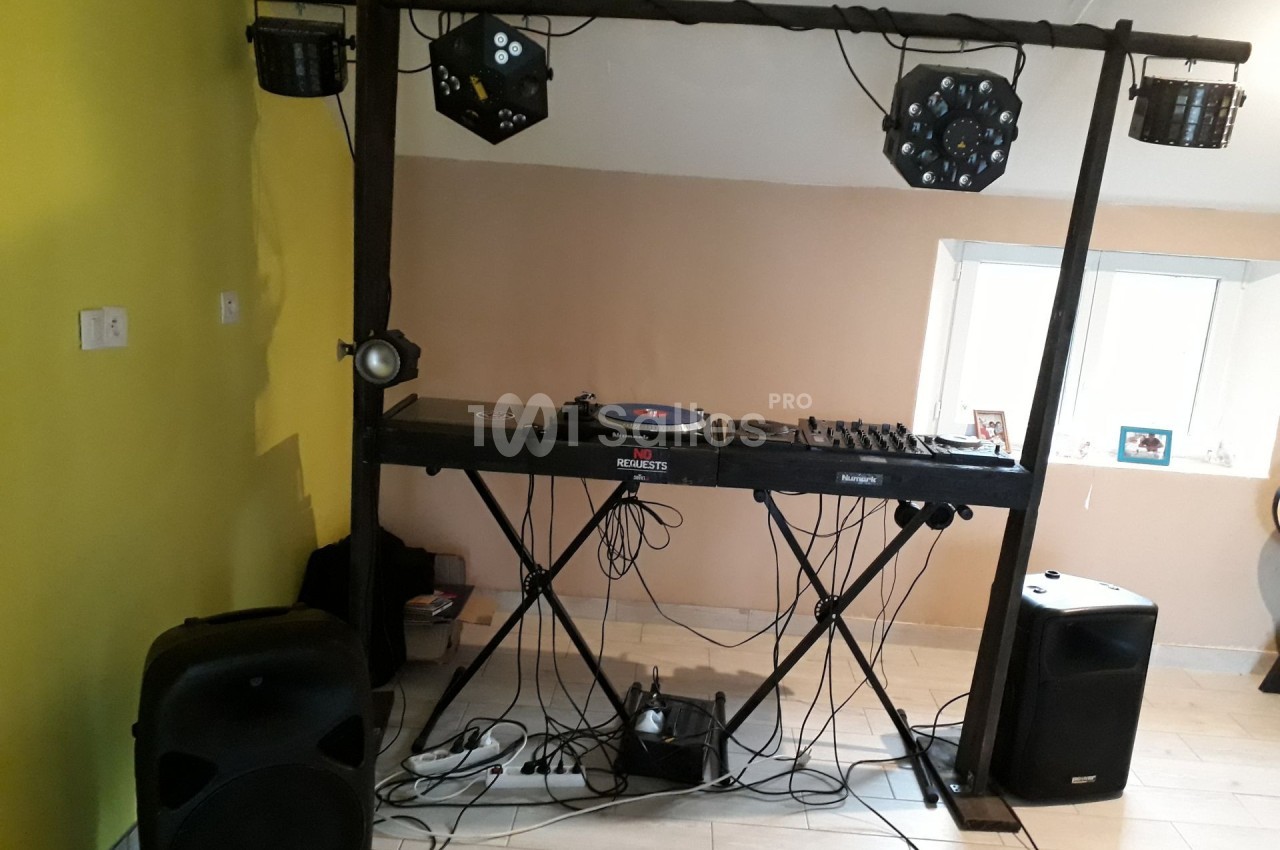 Équipement de DJ avec platine, table de mixage, enceintes et éclairages installés dans une pièce.
