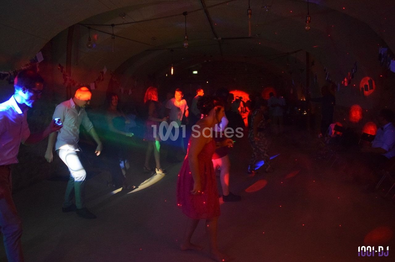 Personnes dansant sous des lumières colorées dans une salle sombre décorée pour une fête.