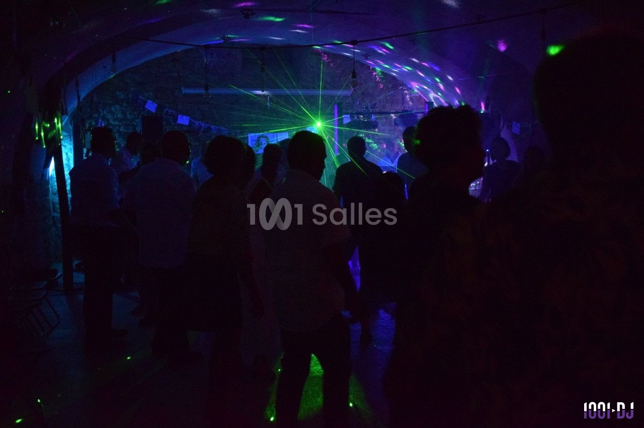 Personnes dansant dans une salle sombre éclairée par des lumières colorées et des lasers.
