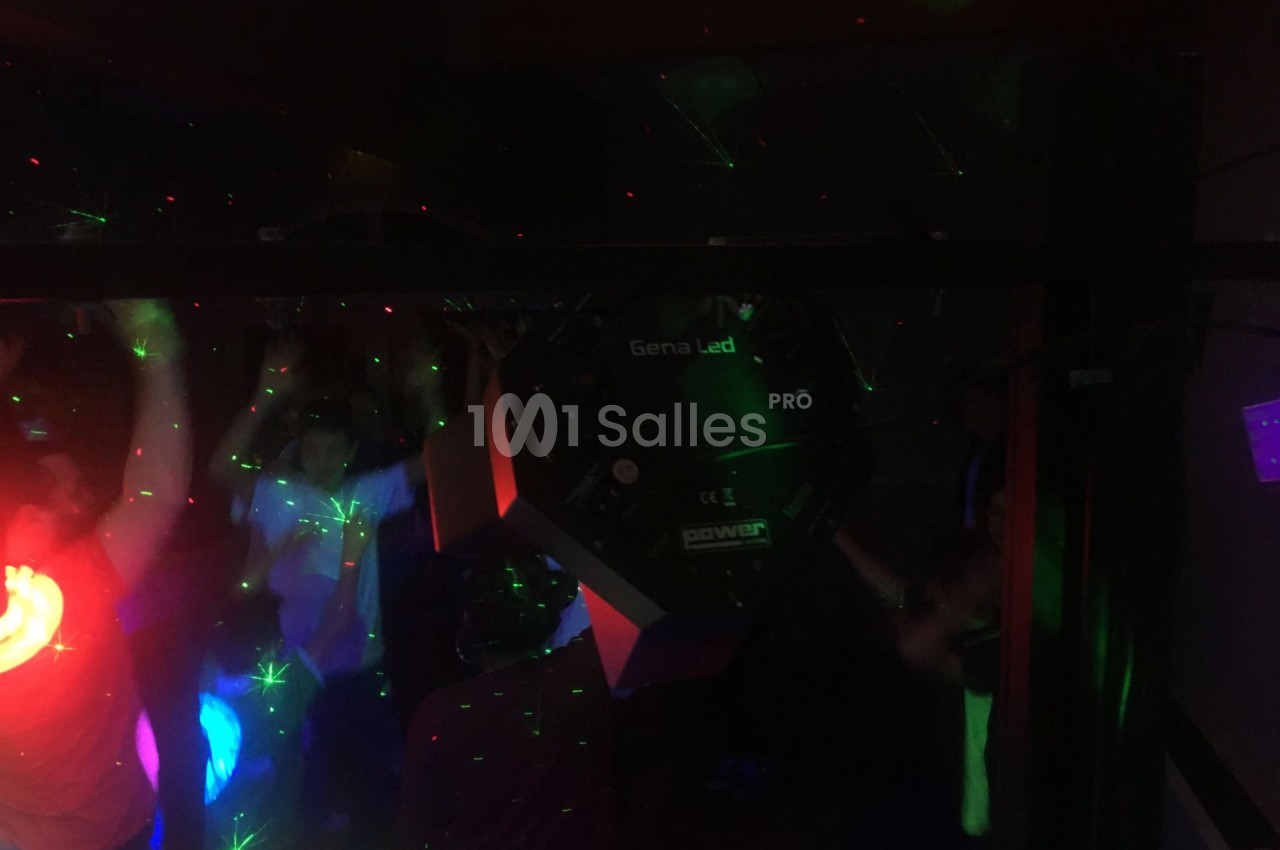 Personnes dansant dans une ambiance sombre avec des lumières colorées et des effets laser.